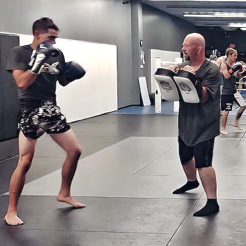 An adult in guard throwing a combination into Thai pads held by his training partner at Rumble Martial Arts in Keswick.