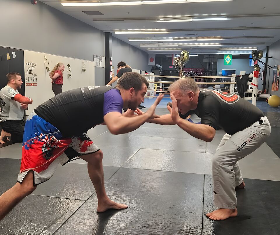 Two adults drilling wrestling takedowns on the mats at Rumble Martial Arts in Keswick.