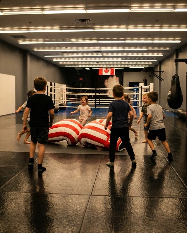 Children playing with jumbo boxing gloves on the mats at Rumble Martial Arts during a birthday party.