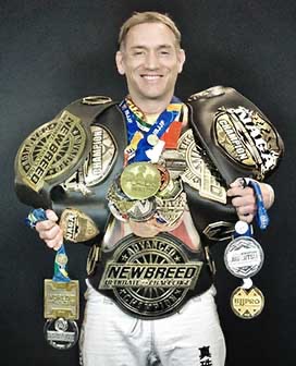 Coach Jones wearing championship belts and medals from international competition.