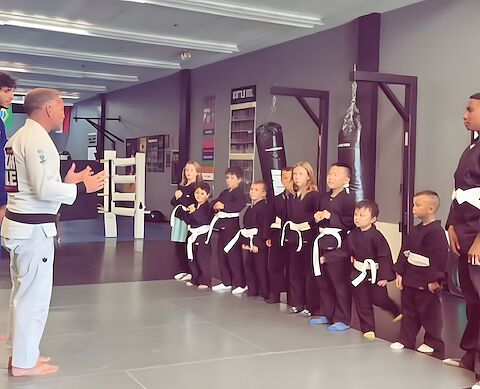 After-school kids lined up in uniform on the mats at Rumble Martial Arts.
